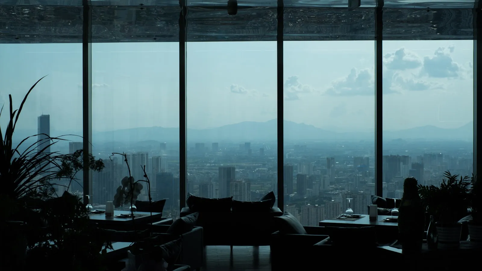 Sala envidraçada no alto de um edifício com vista para a cidade ao fundo