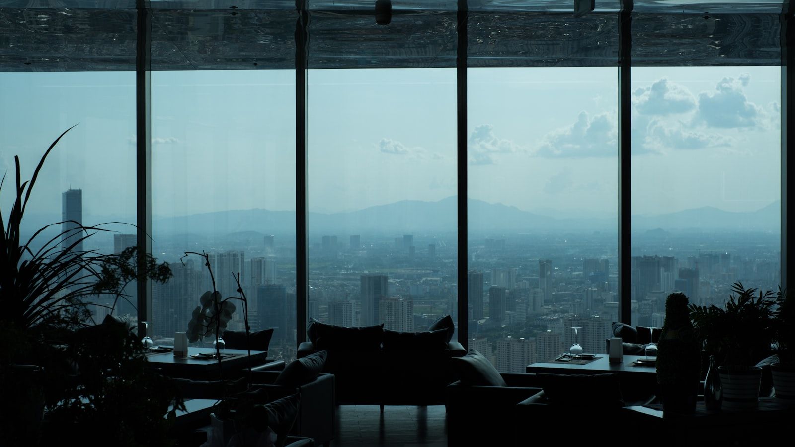 Sala envidraçada no alto de um edifício com vista para a cidade ao fundo